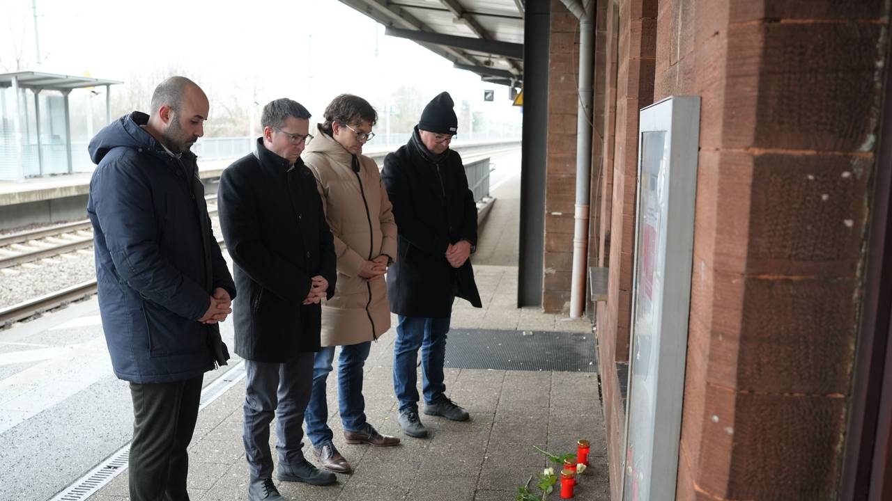Menschen stehen vor Blumen und Kerzen am Bahnsteig im Gedenken an den Tod eines Zugbegleiters. Der Mann war bei einem Angriff im Zug von einem Fahrgast am Montagabend in Rheinland-Pfalz lebensgefährlich verletzt worden und am Morgen infolge der Verletzungen verstorben.