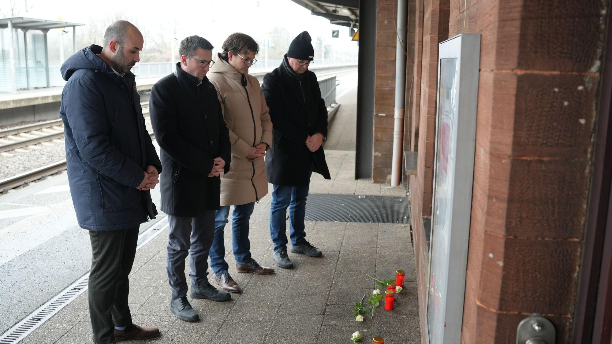 Menschen stehen vor Blumen und Kerzen am Bahnsteig im Gedenken an den Tod eines Zugbegleiters. Der Mann war bei einem Angriff im Zug von einem Fahrgast am Montagabend in Rheinland-Pfalz lebensgefährlich verletzt worden und am Morgen infolge der Verletzungen verstorben.