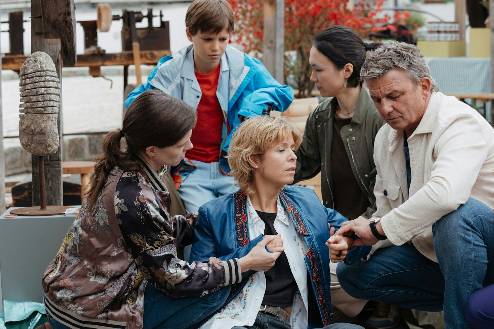 Aufregung auf dem Handwerksmarkt: Anni (vorne Mitte) bricht plötzlich zusammen. Ihre Frau Melanie (links), ihr Sohn Elias (hinten) und Freundin Sarah sind besorgt, während „Bergdoktor“ Dr. Martin Gruber erste Hilfe leistet. (Bild: ZDF/Sabine Finger Fotografie)