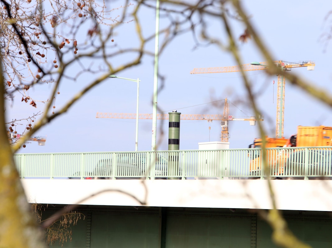 Ein Blitzer steht auf einer Brücke, ein Lkw nähert sich.