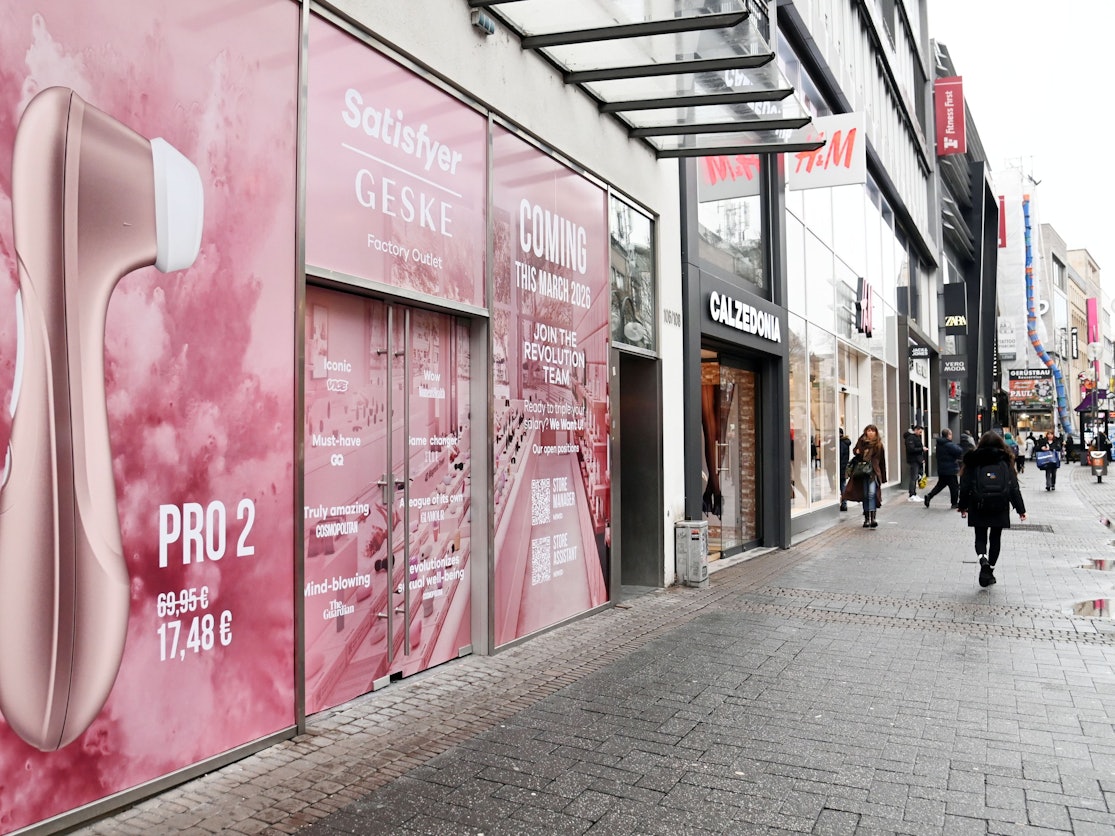 Ein pink beklebtes Schaufenster kündigt einen Geske-Satisfyer-Store auf der Schildergasse an.
