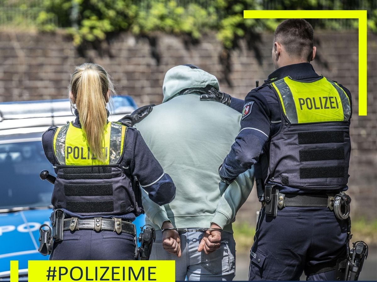 Ein Polizist steht neben einem sichergestellten Auto in einer Halle.