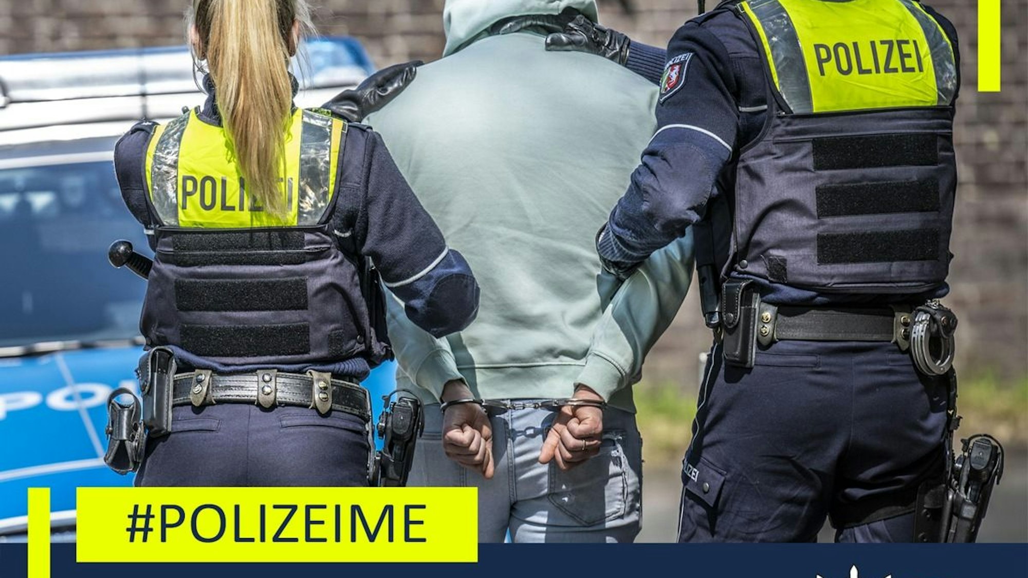 Ein Polizist steht neben einem sichergestellten Auto in einer Halle.