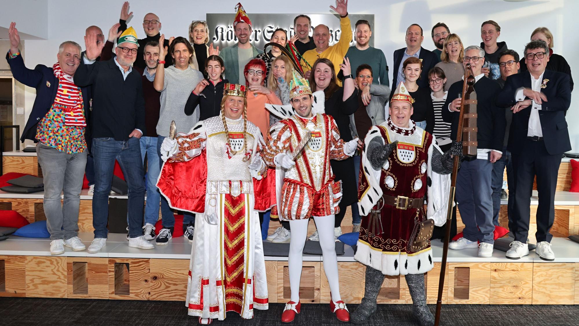 Das Kölner Dreigestirn steht zum Gruppenbild mit den Mitarbeitenden zusammen.
