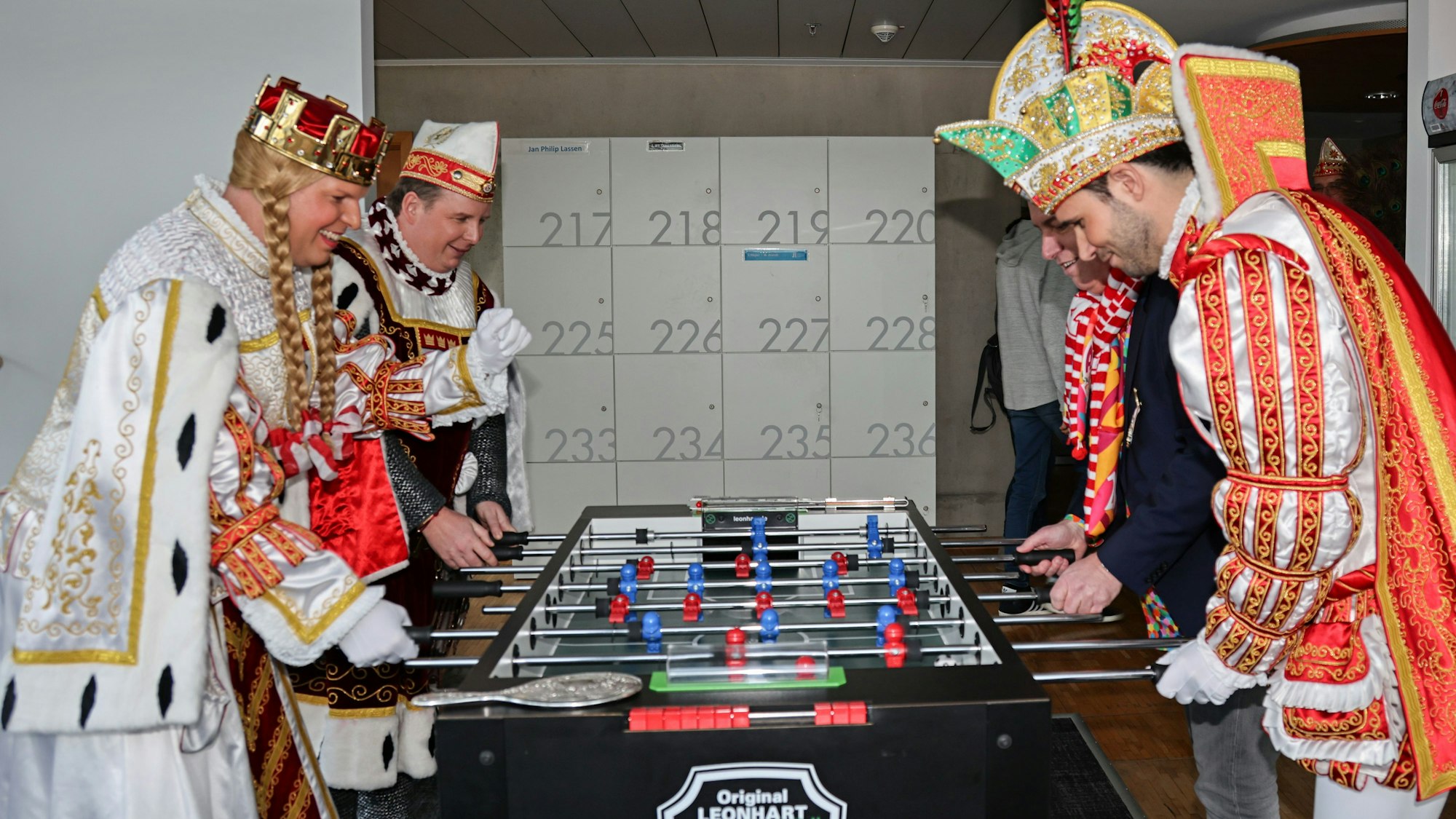 Das Kölner Dreigestirn steht am Kickertisch.