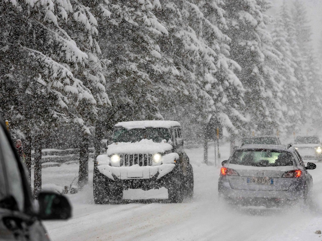 Autofahrer fahren bei starkem Schneefall auf einer Straße in der Nähe des olympischen Austragungsorts Cortina in Norditalien.