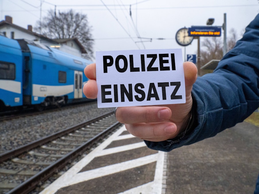 Person hält Schild „Polizeieinsatz“ vor Zug