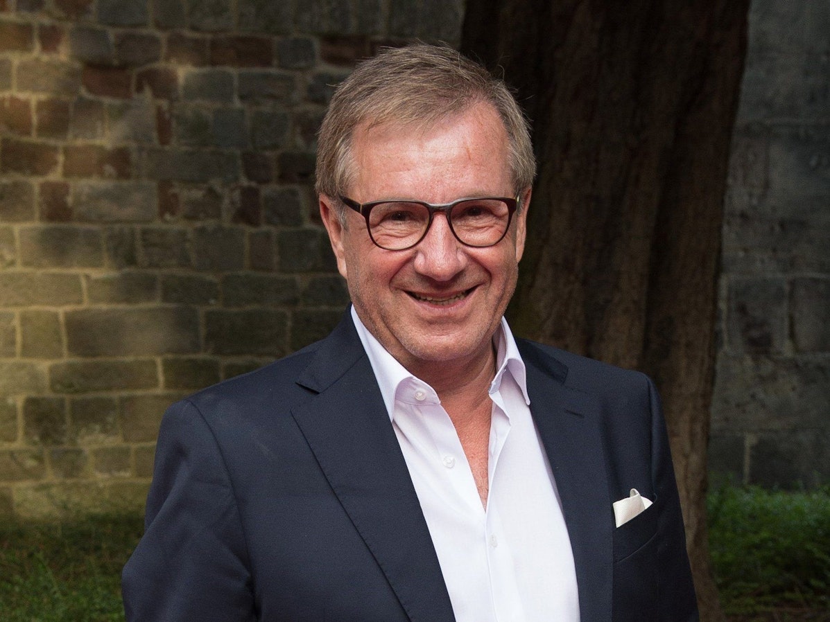 Jan Hofer, Moderator und ehemaliger Tagesschau-Sprecher, steht vor einer Backsteinwand und lächelt in die Kamera.