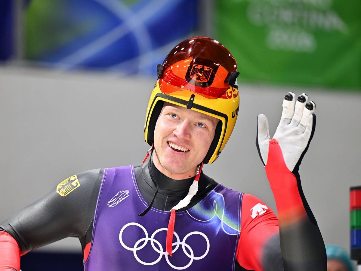 Rennrodler Max Langenhan winkt lächelnd den Fans zu.