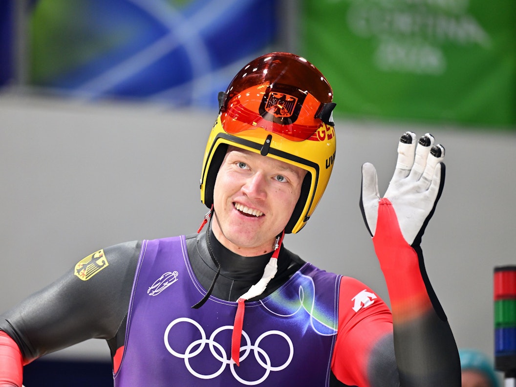 Rennrodler Max Langenhan winkt lächelnd den Fans zu.