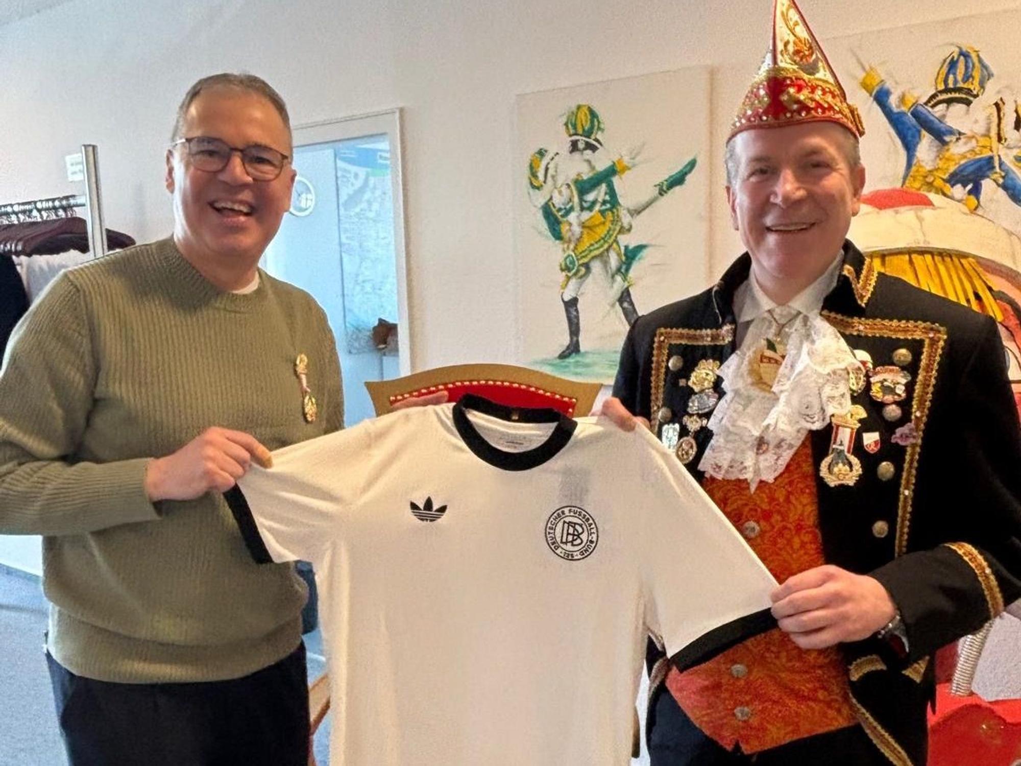 Andreas Rettig gibt Christoph Kuckelkorn ein Trikot.