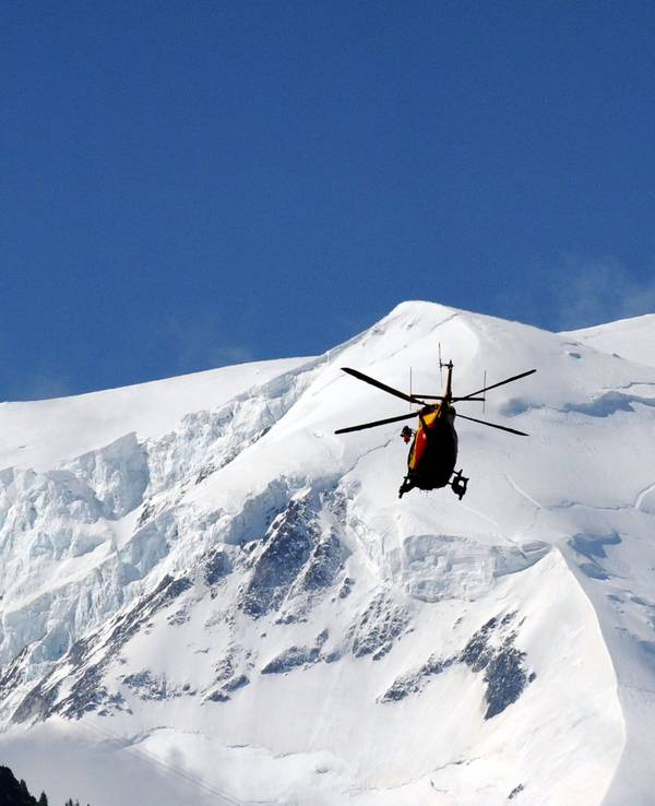Ein Hubschrauber fliegt über schneebedeckte Berge.