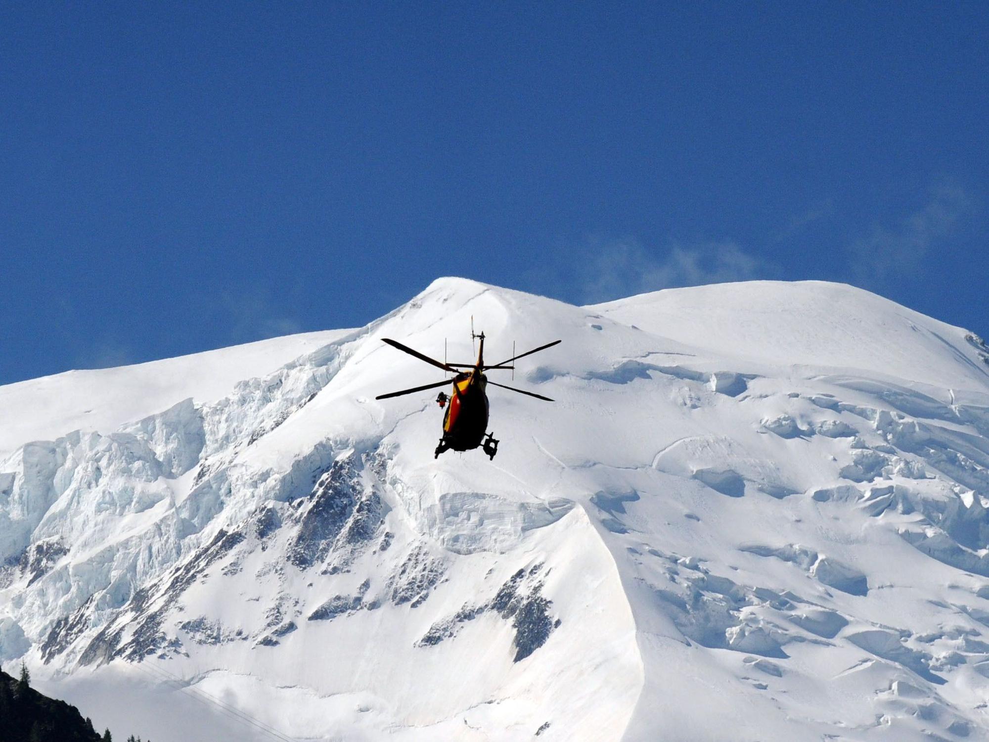 Ein Hubschrauber fliegt über schneebedeckte Berge.