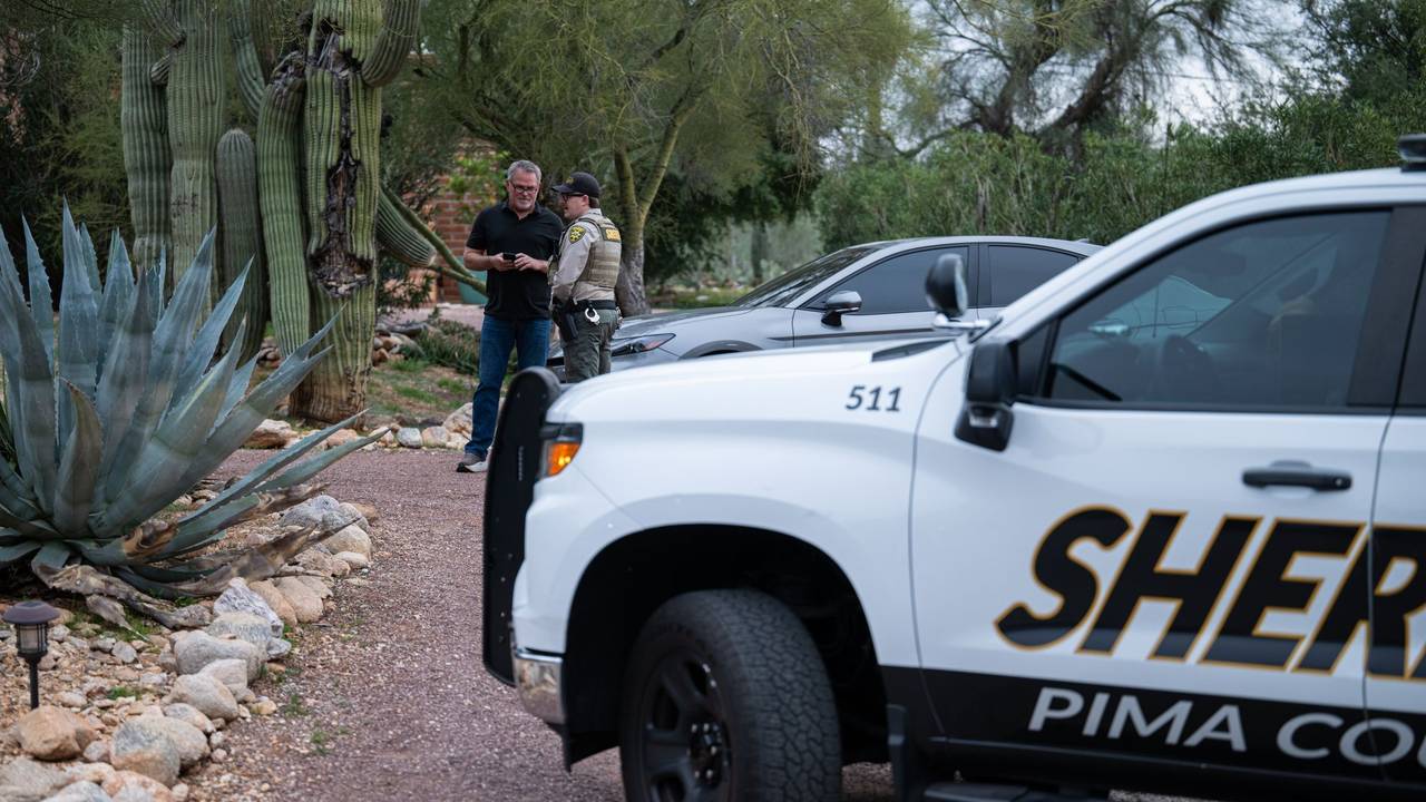 Ein Beamter des Pima County Sheriffs unterhält sich mit einem privaten Sicherheitsbeamten vor dem Haus von Nancy Guthrie. Auf der Türschwelle wurden Blutspuren der Entführten gefunden.