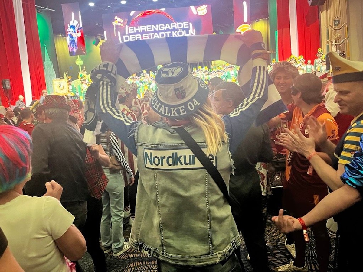 Ein Schalke-Fan hält einen blau-weißen Schal im Publikum hoch.