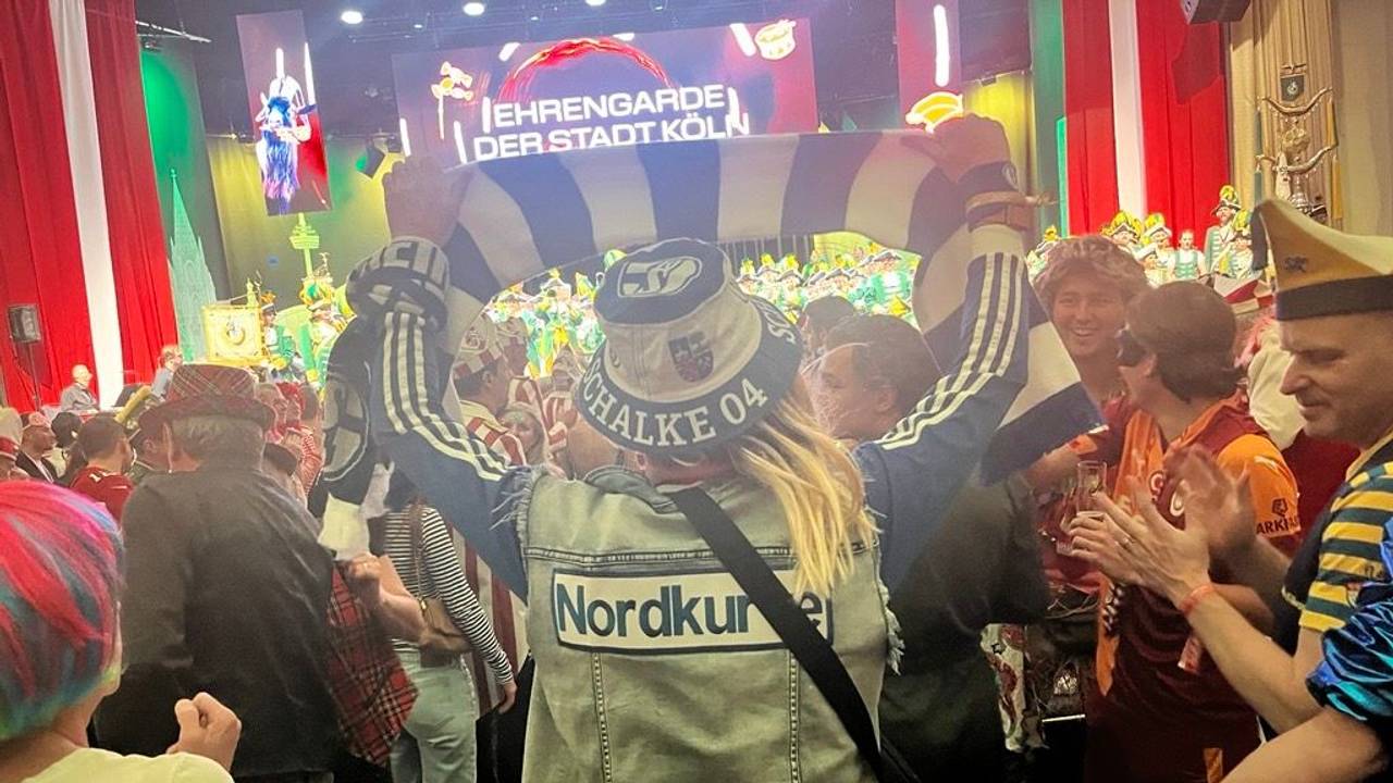 Ein Schalke-Fan hält einen blau-weißen Schal im Publikum hoch.