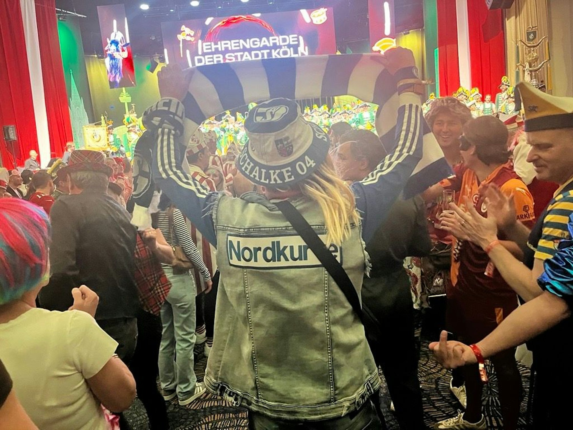 Ein Schalke-Fan hält einen blau-weißen Schal im Publikum hoch.