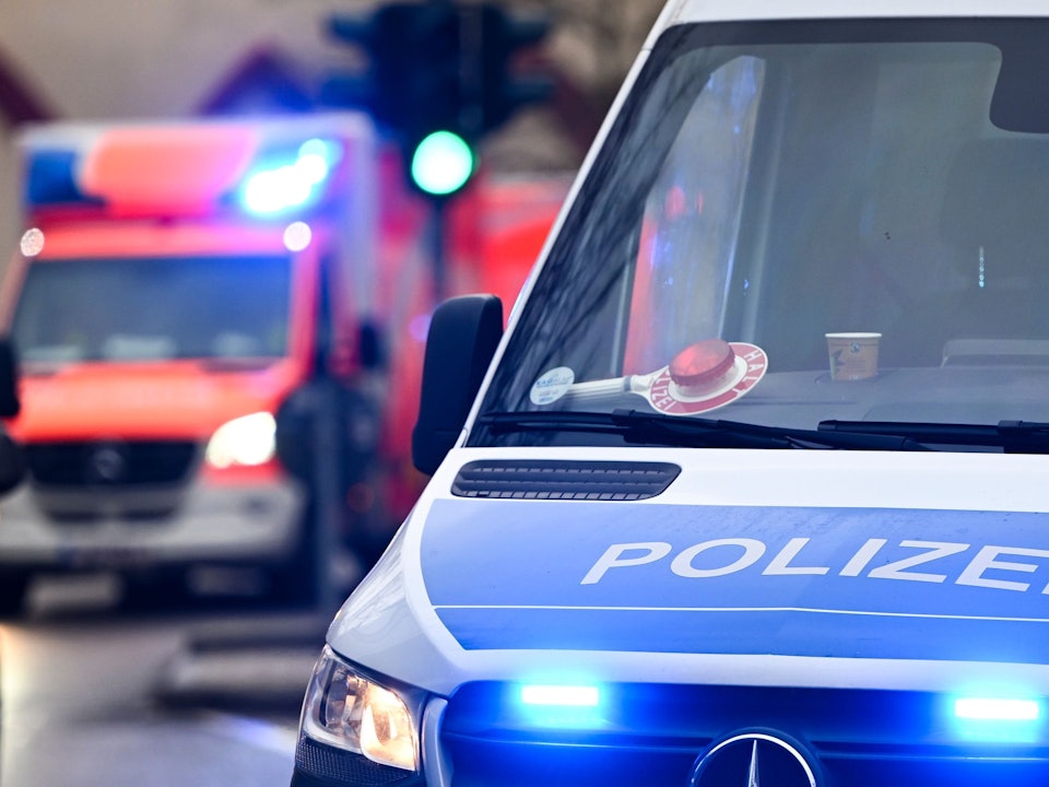 Die Polizei fahndet nach zwei in Monheim gemeldeten Männern im Alter von 19 und 37 Jahren. Das Symbolfoto zeigt ein Polizeiauto und einen Rettungswagen mit Blaulicht.