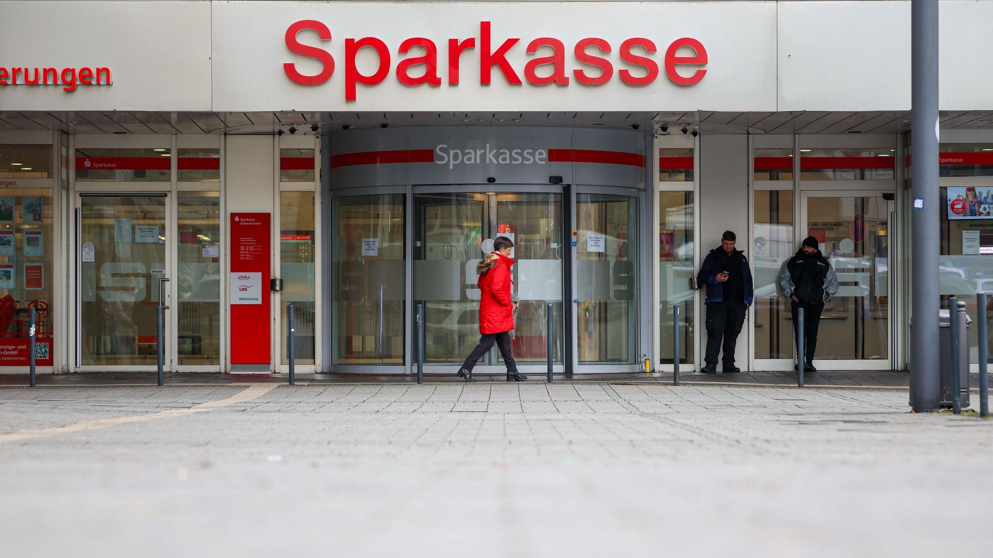Security-Mitarbeiter stehen vor der Sparkasse Gelsenkirchen, die auf dem Archivbild noch geschlossen ist. Vier Fehlalarme sorgen aktuell für Einsätze.