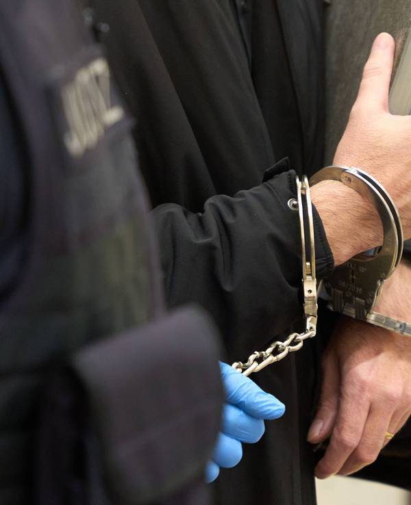Justizbeamte führen einen Angeklagten in den Gerichtssaal des Saarländischen Oberlandesgerichts.