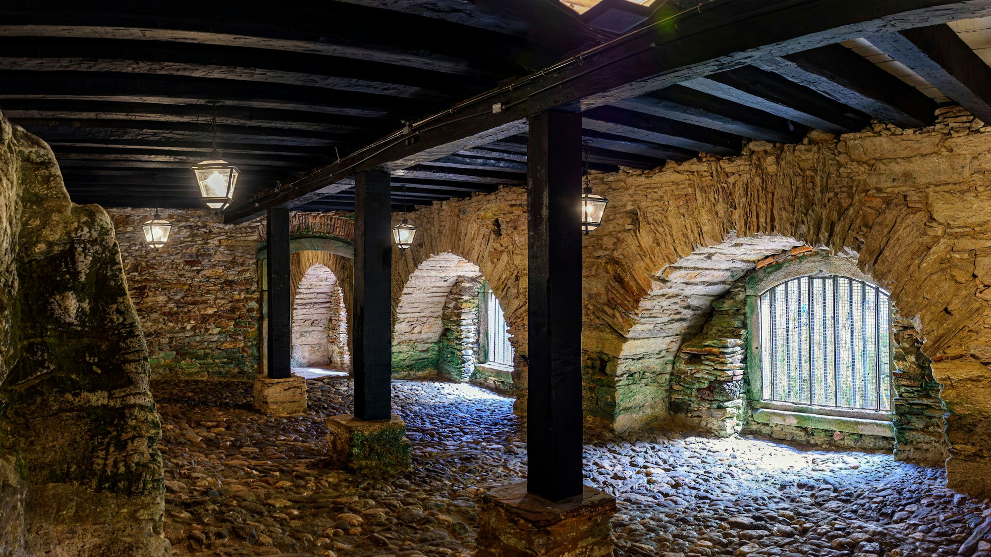 Steinmauerwerk, Bögen, Holzbalken, Laternen und Pflasterboden