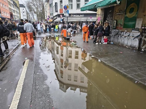 Auf der Zülpicher Straße staut sich das Regenwasser. Der Laune der Jecken tut dies keinen Abbruch.