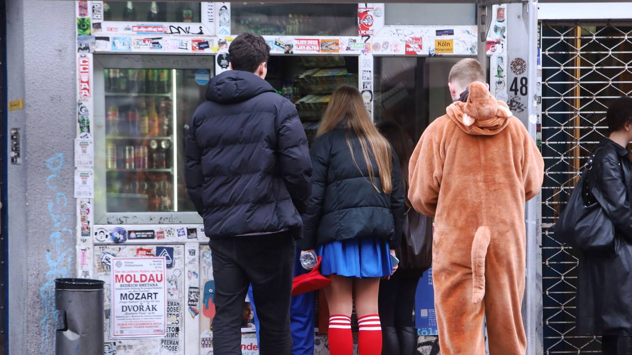 Verkleidete Jugendliche stehen an einem Kiosk.
