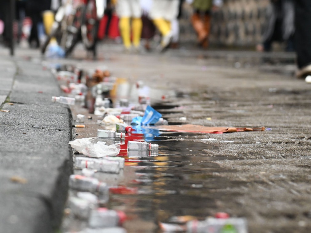 Leere Alkoholfläschchen liegen am Straßenrand in einer Pfütze.