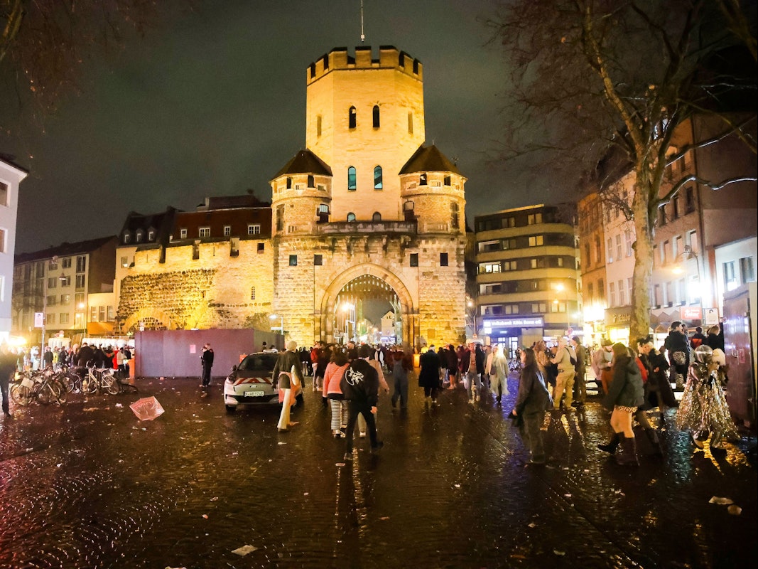 Vor einem historischen Burgtor feiern verkleidete Menschen.