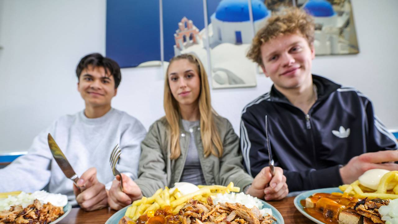 Nickolas Krugmann (von links), Antonija Dreznjak und Lukas Kampen sitzen vor ihren Taxi-Tellern in einem Imbiss in Essen. Pommes, Currywurst und dazu massenweise Gyros mit Zwiebeln: Im Ruhrgebiet sorgt der Taxi-Teller längst für Begeisterung bei Fast-Food-Fans.
