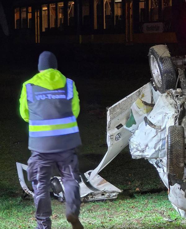 Ein Polizist steht nach einem Unfall neben einem auf dem Dach liegenden Auto. Beim Überqueren eines unbeschrankten Bahnübergangs war der Wagen von einem Zug erfasst worden. Der 18-jährige Fahrer erlag im Krankenhaus seinen Verletzungen.