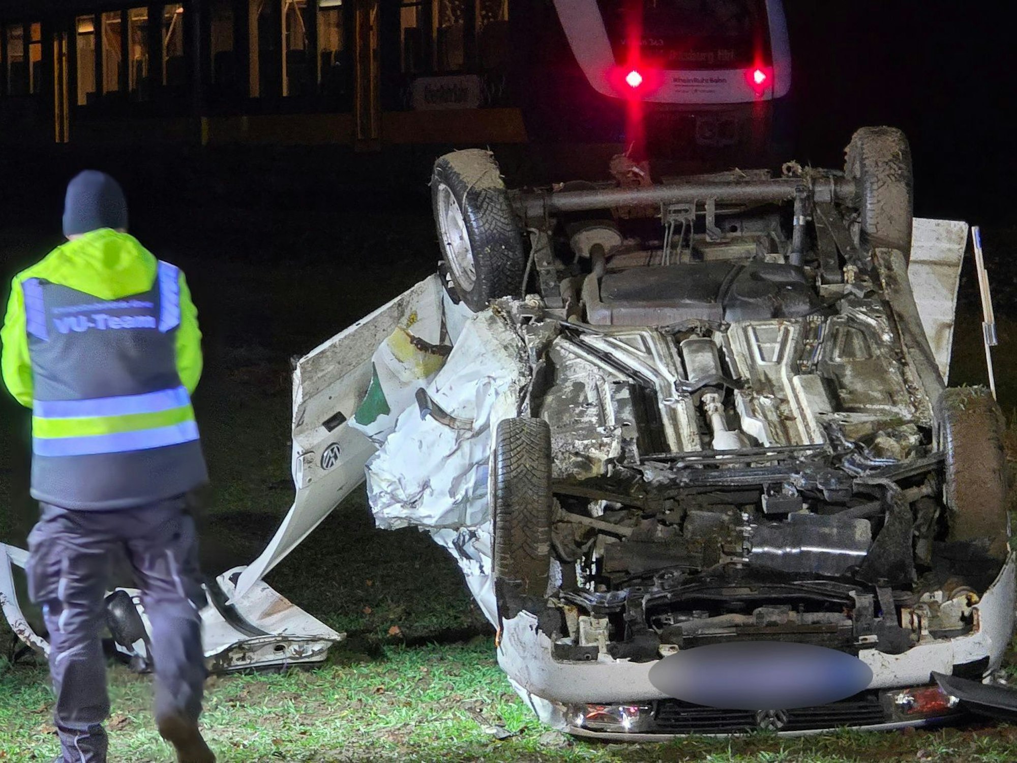 Ein Polizist steht nach einem Unfall neben einem auf dem Dach liegenden Auto. Beim Überqueren eines unbeschrankten Bahnübergangs war der Wagen von einem Zug erfasst worden. Der 18-jährige Fahrer erlag im Krankenhaus seinen Verletzungen.