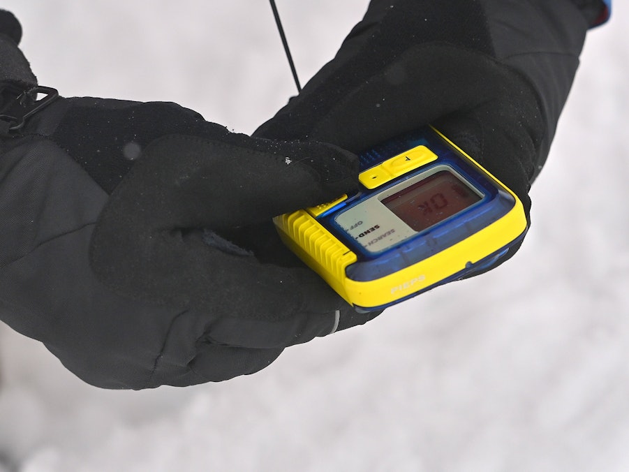 Hand im Handschuh hält Lawinensuchgerät