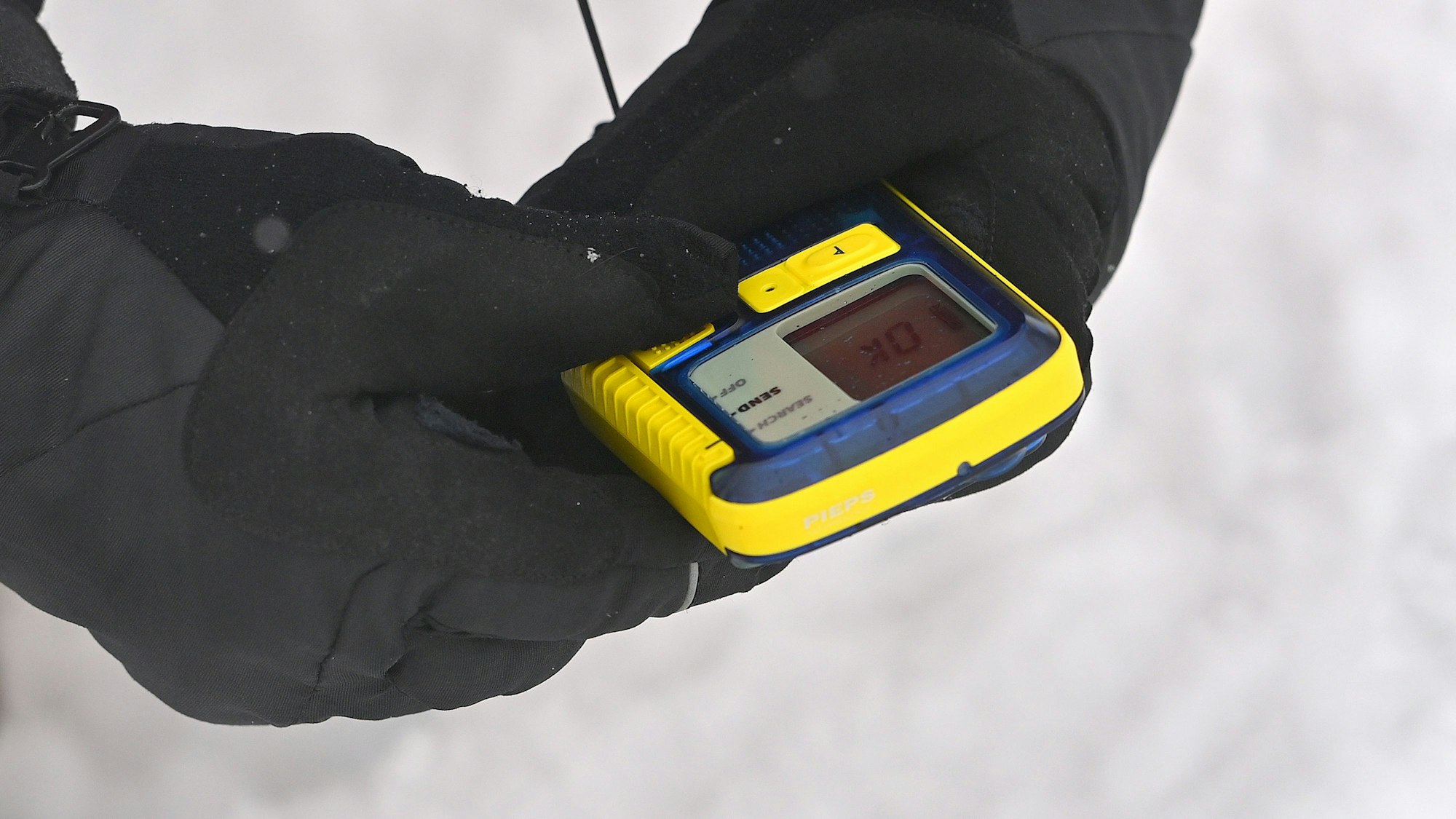 Hand im Handschuh hält Lawinensuchgerät