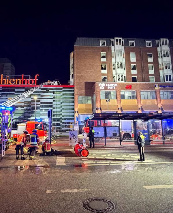 Einsatzkräfte der Feuerwehr arbeiten auf einer Drehleiter an einem Wohnhaus neben dem Einkaufszentrum Sophienhof in der Kieler Innenstadt.