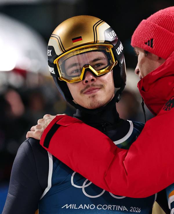 Philipp Raimund wird im Olympia-Wettbewerb im Skispringen von Andreas Wellinger getröstet.