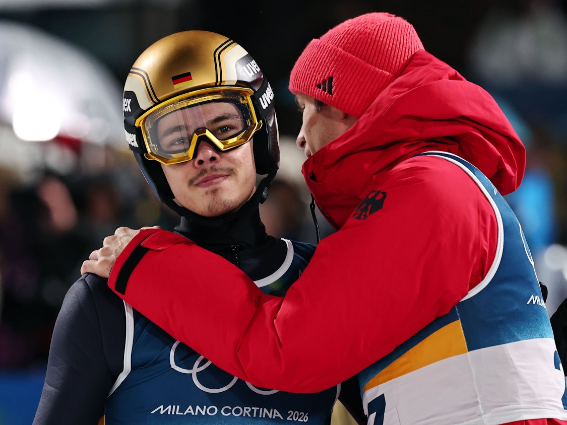 Philipp Raimund wird im Olympia-Wettbewerb im Skispringen von Andreas Wellinger getröstet.
