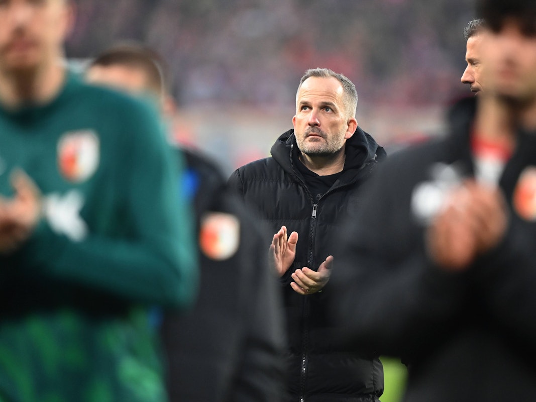 Trainer Manuel Baum vom FC Augsburg klatscht vor der Fankurve.