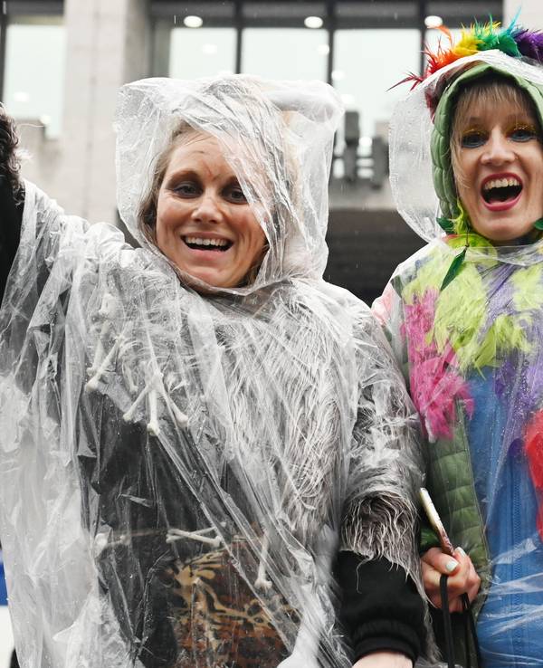 Jecke schützen ihre Kostüme im Regen mit einem Poncho.