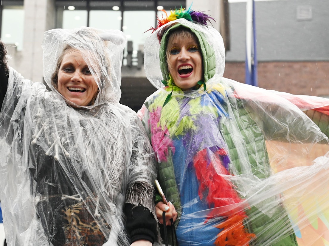 Jecke schützen ihre Kostüme im Regen mit einem Poncho.