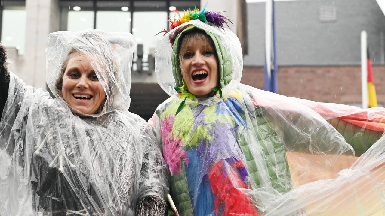 Jecke schützen ihre Kostüme im Regen mit einem Poncho.