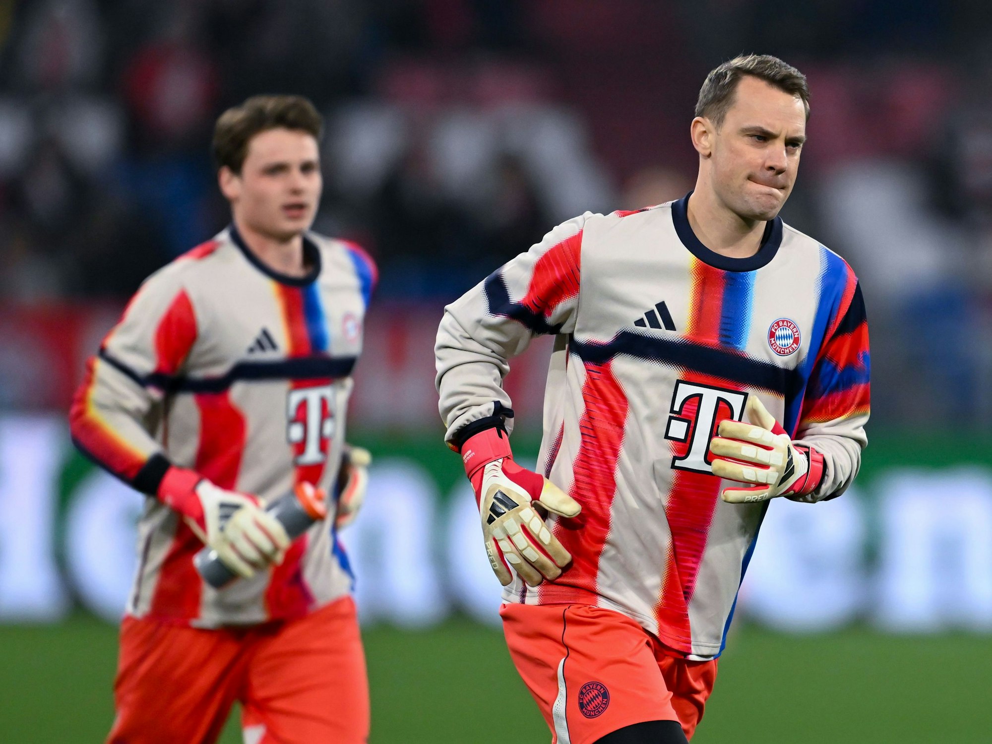 Bayern-Torhüter Manuel Neuer und Jonas Urbig beim Warmmachen auf dem Rasen.