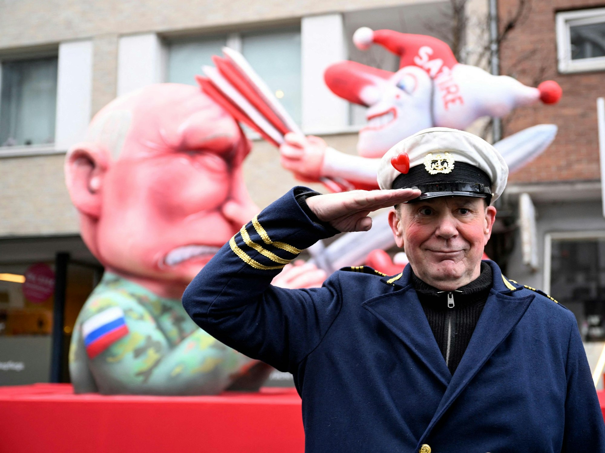 Kleiner Blick nach Düsseldorf: Jacques Tilly posiert vor seinem aktuellen Werk. Es zeigt einen kleinen Narren, der auf Wladimir Putin einschlägt.
