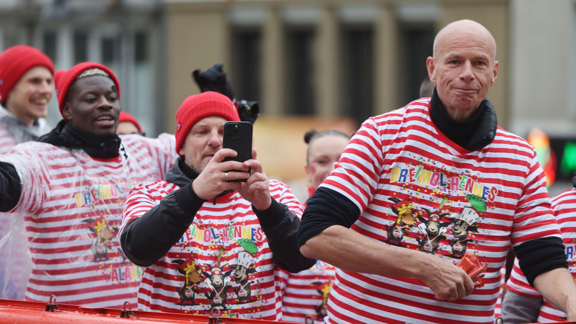 Lukas Kwasniok macht beim Rosenmontagszug Fotos mit dem Handy. Er fährt mit Ragnar Ache und Jörn Stobbe auf dem Wagen des 1. FC Köln.