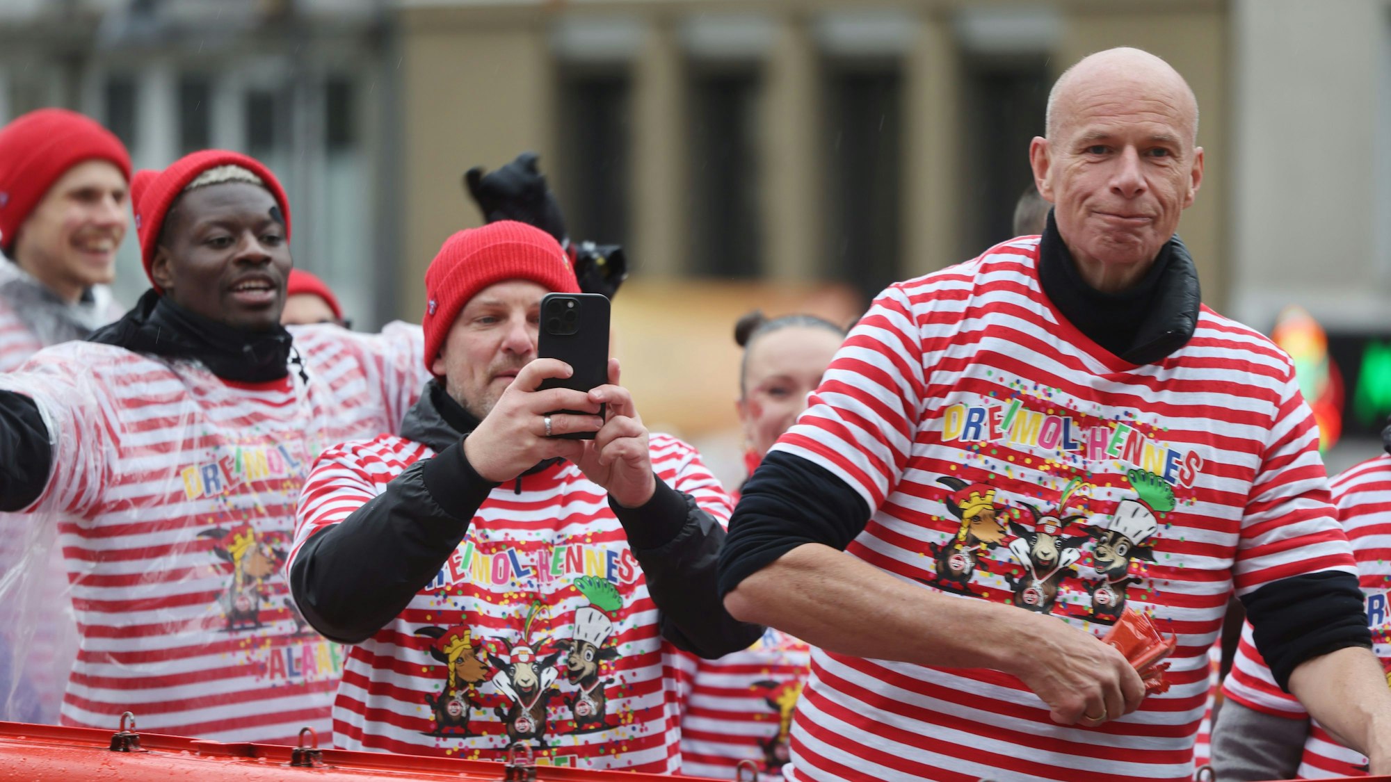 Lukas Kwasniok macht beim Rosenmontagszug Fotos mit dem Handy. Er fährt mit Ragnar Ache und Jörn Stobbe auf dem Wagen des 1. FC Köln.