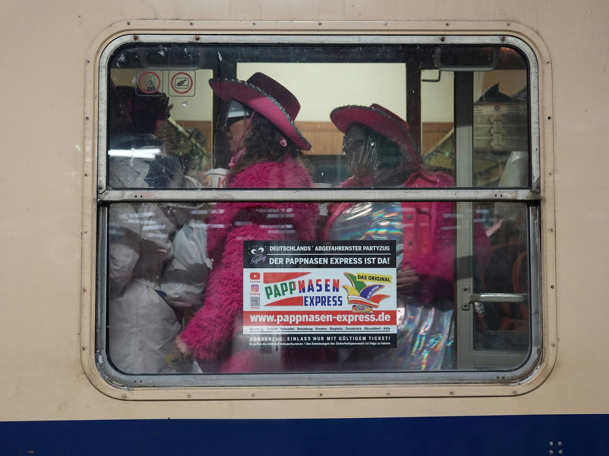 Karnevalisten gehen während der Abfahrt aus dem Bahnhof Bremen durch ein Zugabteil des Pappnasen Express auf der Fahrt von Hamburg nach Köln.