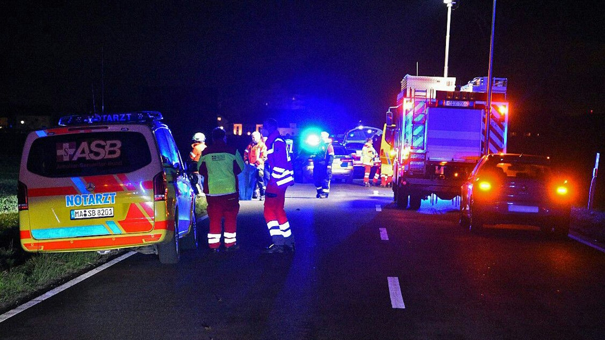 Einsatzkräft stehen auf einer Straße.