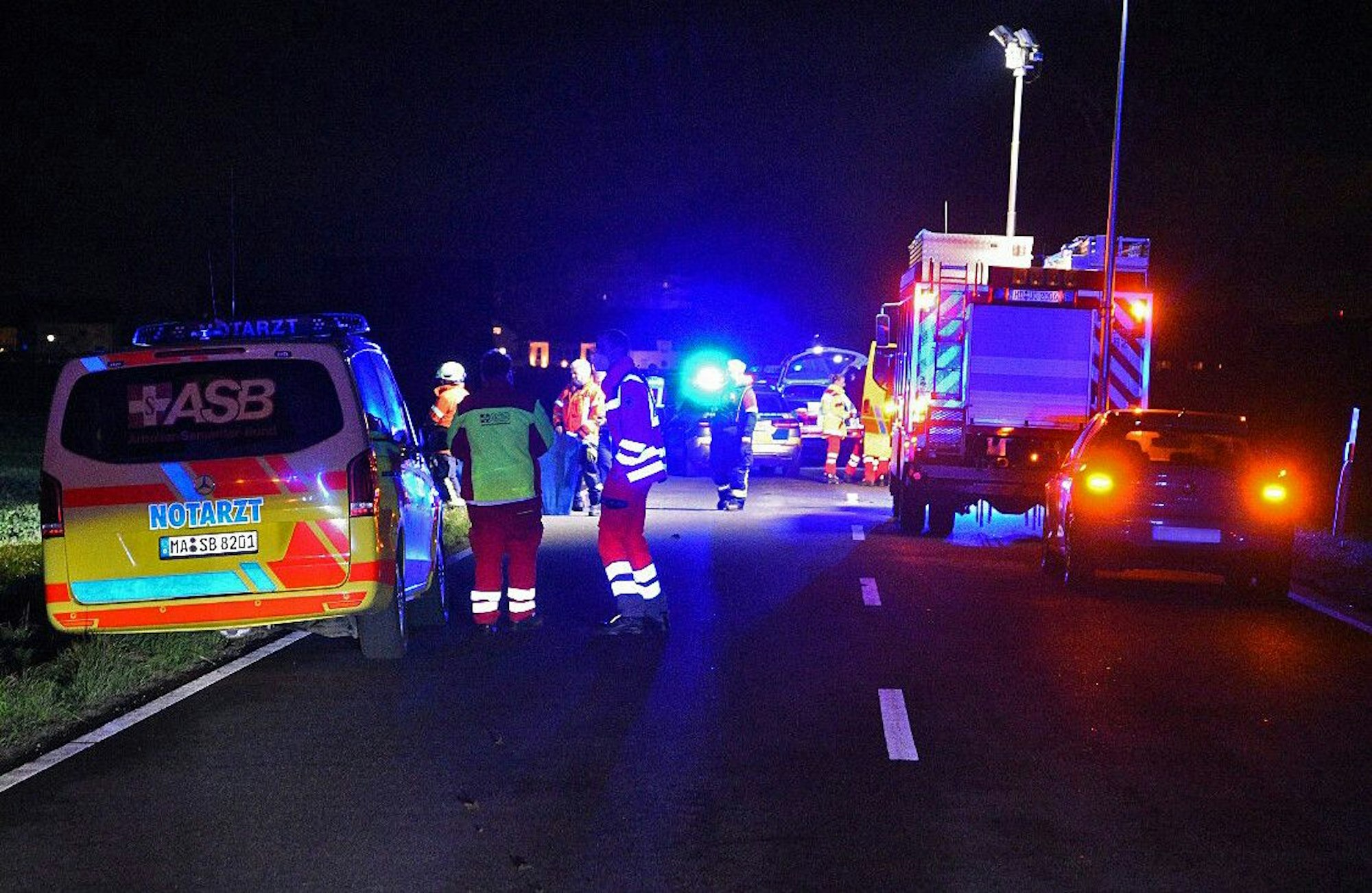 Kräfte und Fahrzeuge von Rettungsdienst, Polizei und Feuerwehr sind nachts auf einer Straße im Einsatz.
