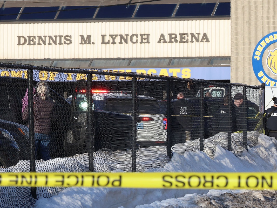 Einsatzkräfte stehen vor einer Halle, im Vordergrund Absperrband der Polizei.