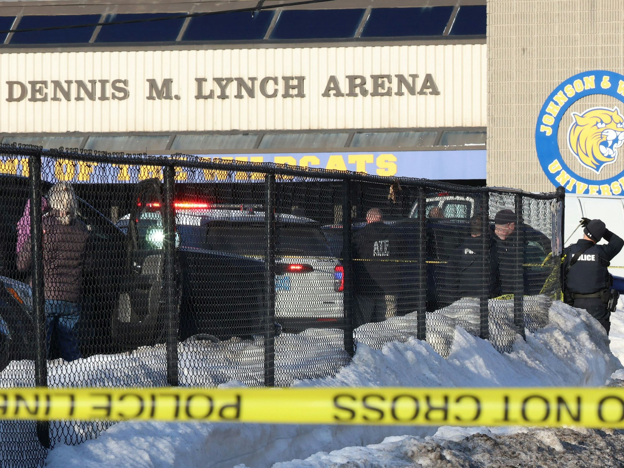 Einsatzkräfte stehen vor einer Halle, im Vordergrund Absperrband der Polizei.